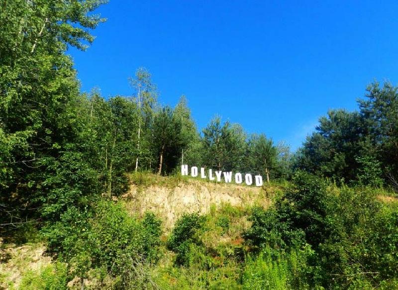 Słynny napis Hollywood przy drodze pomiędzy Słodkowem Trzecim a Szastarką pośród drzew na tle błękitnego nieba
