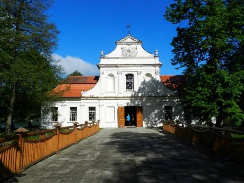 Frontowa ściana kościoła w Zwierzyńcu na tle drzew i błękitnego nieba